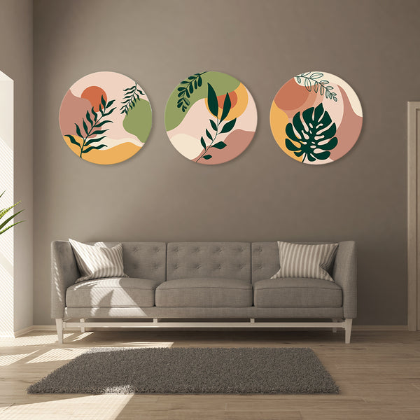 Three circular wall art pieces with leaf designs above a gray sofa in a living room.