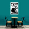 Table with two chairs against a teal wall with a framed black and white cat illustration.