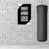 Motivational poster with quote next to a punching bag against a brick wall.