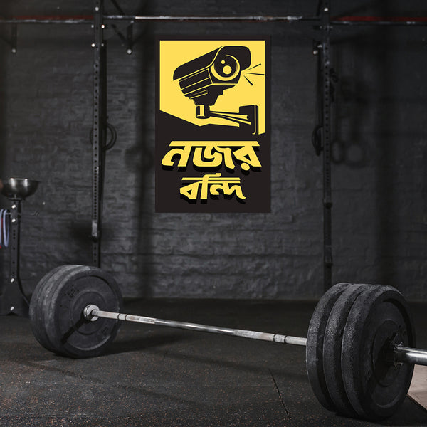 Barbell with weights in a gym setting featuring a security camera sign.