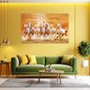 Living room with green sofa, coffee table, and wall art of running horses.