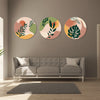 Three circular wall art pieces with leaf designs above a gray sofa in a living room.