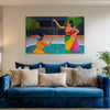 Blue sofa with decorative pillows and a colorful painting of two women on the wall.