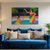 Blue sofa with decorative pillows and a colorful painting of two women on the wall.