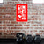 Black kettlebell and dumbbells against a brick wall with a red and white logo above.