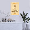 Decorative wall art with praying hands and text on a yellow background, placed above a white cabinet with plants.